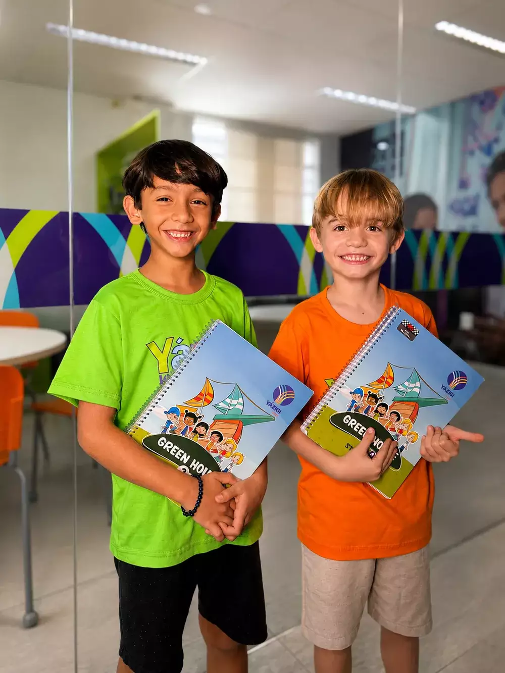 Dois alunos do Yázigi segurando materiais didáticos da escola de idiomas
