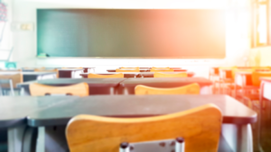 cadeira de madeira e mesa escolar em destaque, ao fundo uma lousa verde que juntos representam o tema deste artigo que é como abrir uma escola do zero
