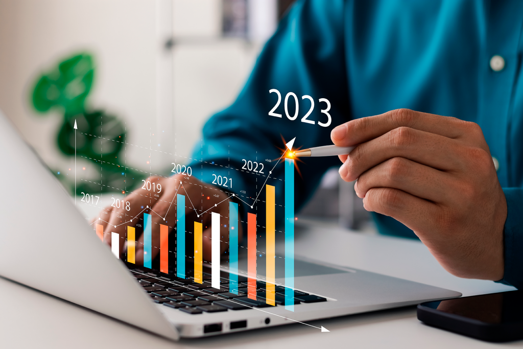 homem de camisa azul, segurando uma caneta e na frente do seu computador mostra os anos até chegar em 2023, mostrando negócio para abrir em 2023